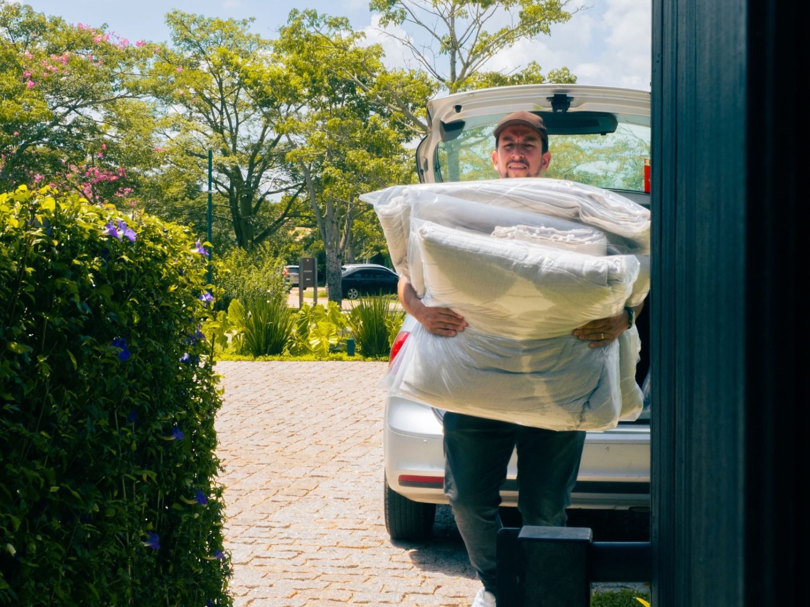 Profissional da Prime retirando as cortinas embaladas do porta-malas na casa da cliente